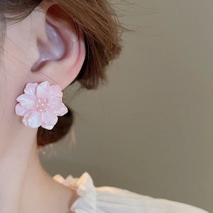 Dettaglio di orecchini a lobo a forma di fiore rosa con petali e perla centrale