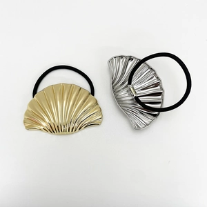 Close-up of gold and silver shell-shaped hair ties with black elastic bands on white background