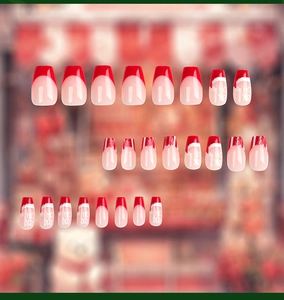 Close-up of French Christmas press-on nails featuring red and nude festive patterns