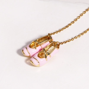 Detail shot of the pink enamel ballet slipper pendant with gold edging on a dainty chain