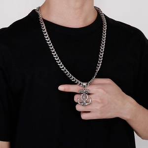 Gros plan du pendentif ancre en acier argenté avec croix sur un t-shirt noir sobre