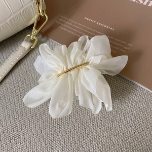 Détail d'une élégante pince à cheveux fleur en mousseline blanche avec centre en métal doré