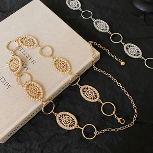 Detailed close-up of gold and silver vintage waist chains with hollow oval and pearl link