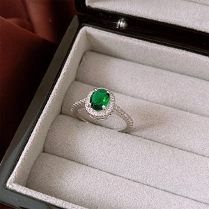 Detailed macro view of an emerald green oval zircon ring in a gray jewelry box