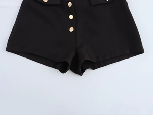 Detailed view of women's black low-rise shorts featuring three decorative gold round buttons