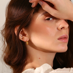 Detail shot of a model wearing a minimalist 18K gold-plated twisted rope stud earring