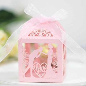 Pink laser-cut wedding favor box with ribbon featuring bride and groom silhouette design