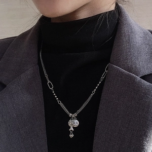 Detail of vintage silver layered necklace with smiley, fish, and heart charms on a model