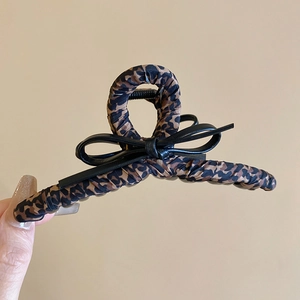 Close-up of geometric leopard print hair claw clip with black fabric bow decoration