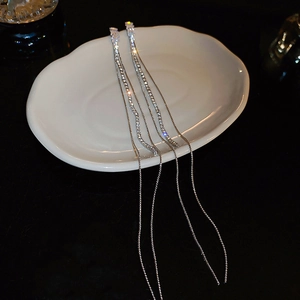 Detailed view of elegant silver tassel earrings with sparkling zircon stones on white ceramic