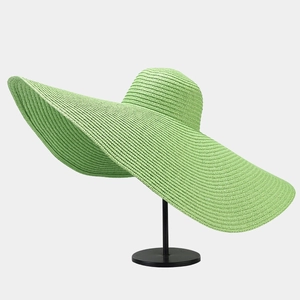 Detail of light green wide-brim straw sun hat with woven texture on a display stand