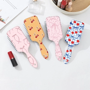 Detailed top view of various cute cherry and bow patterns on professional hair brushes