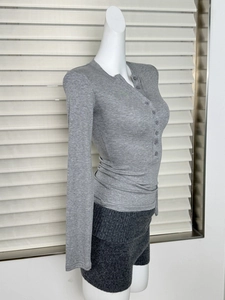 Détail d'un haut henley en maille grise avec boutonnage et texture manches longues