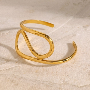 Minimalistischer goldener Edelstahl-Armreif mit asymmetrischem Design auf Naturstein