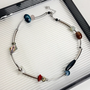 Detail of colorful natural stones and silver metal tube beads on a handcrafted necklace