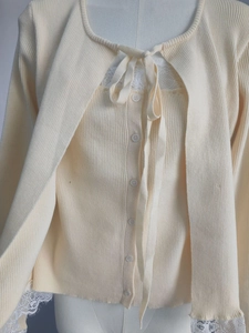 Détail de l'ensemble en tricot crème avec texture verticale et bordure en dentelle