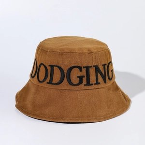 Détail de la broderie noire DODGING sur un chapeau bob en coton caramel pour l'été