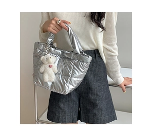 Close-up of silver quilted down bag with a cute white plush bear pendant detail
