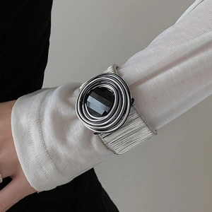 Detail of a wide silver multilayered open bangle featuring a large faceted black gemstone