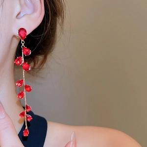 Detail of red water drop zircon earrings in gold plating worn by a model in a warm setting