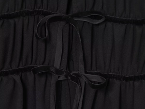 Detail der Samtschleife und der plissierten Georgette-Stoffstruktur einer schwarzen Bluse