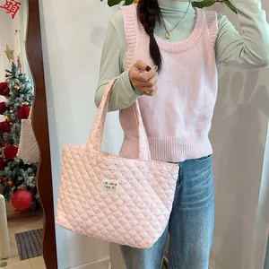 Detail of pink quilted tote bag featuring floral pattern and woven brand logo tag