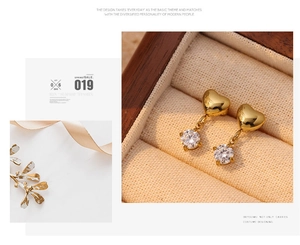 Close-up of golden heart earrings with sparkling zircon pendants in a luxury gift box