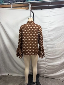 Détail du chemisier en mousseline à pois marrons avec poignets à volants élégants au dos