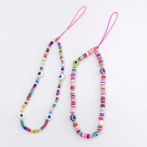 Detail of beaded phone straps with evil eye charms and colorful clay beads on grey background