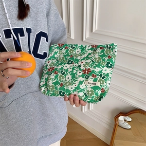 Floral cotton makeup bag with green patterns and brand tag held by a model