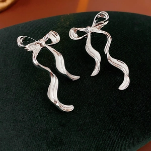 Gros plan de boucles d'oreilles nœud argenté avec rubans sur présentoir en velours