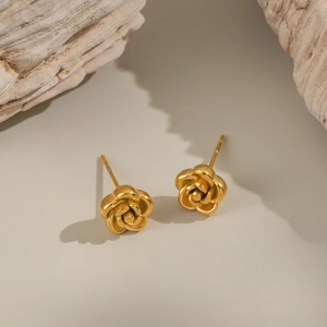 Macro shot of elegant golden rose stud earrings on natural stone texture background