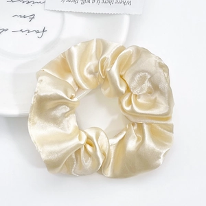 Elegant champagne satin scrunchie with silk luster on a minimalist white backdrop
