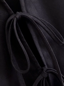 Detailed macro view of black faux suede fabric texture and lace-up bow design on the top