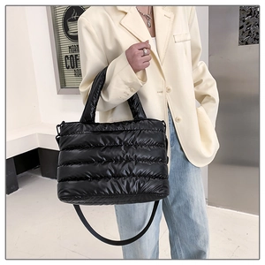 Detail of black quilted puffer tote bag featuring glossy fabric and adjustable shoulder strap