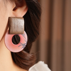 Close-up of geometric wood and resin drop earrings with bamboo leaf print on a model