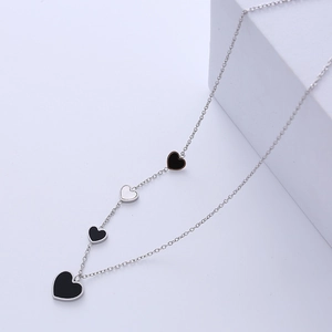 Minimalist silver chain necklace featuring four black and white heart charms on steps