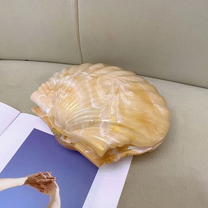 Detail of shell-shaped clutch bag with amber marble texture and gold metal clasp
