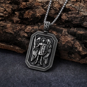 Macro shot of Archangel Michael shield pendant in antique silver on bark background
