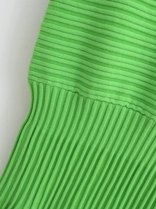 Detail of green knit dress showing high-quality ribbed texture and fabric patterns