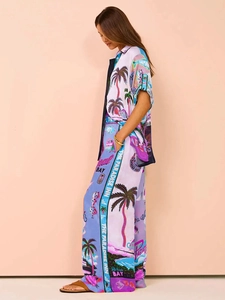 Side view of woman in tropical print two-piece set with short sleeve shirt and wide leg pants