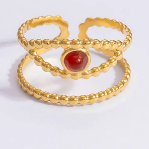 Close-up of gold beaded double-layer ring featuring a red oval gemstone centerpiece