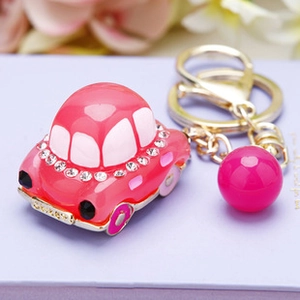 Detailed view of a pink crystal-studded car keychain with golden ring and pink bead