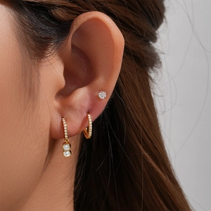 Detailed close-up of gold-plated earring set with micro-pave crystals on model's ear