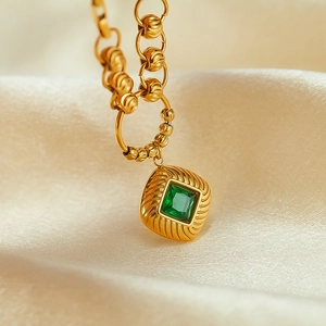 Macro view of vintage gold necklace with square emerald zircon and textured floral beads