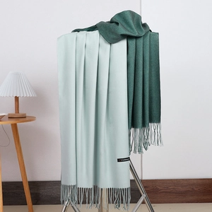 Detail view of double-sided cashmere scarf showing soft texture and fringed edges in green