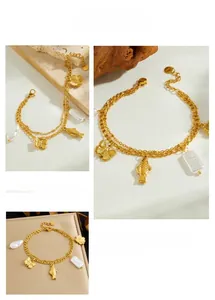 Detail of double-layer gold plated bracelet with butterfly, fish and pearl charms