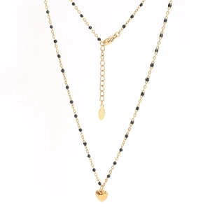 Détail du collier en chaîne dorée avec perles noires, pendentif cœur poli et fermoir