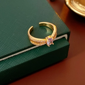 Nahaufnahme des goldfarbenen Rings mit lila Edelstein und Zirkonia auf grüner Box