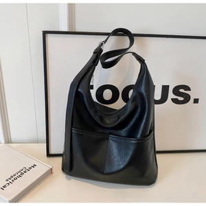 Detail of black faux leather shoulder bag with adjustable strap and silver metal buckle